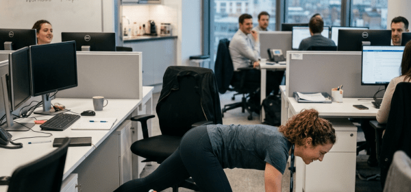 Woman performing a plank exercise on a yoga mat in an office workspace